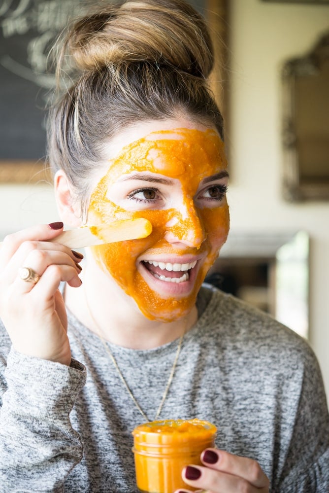smiling woman with a bun and applying a DIY pumpkin facial mask