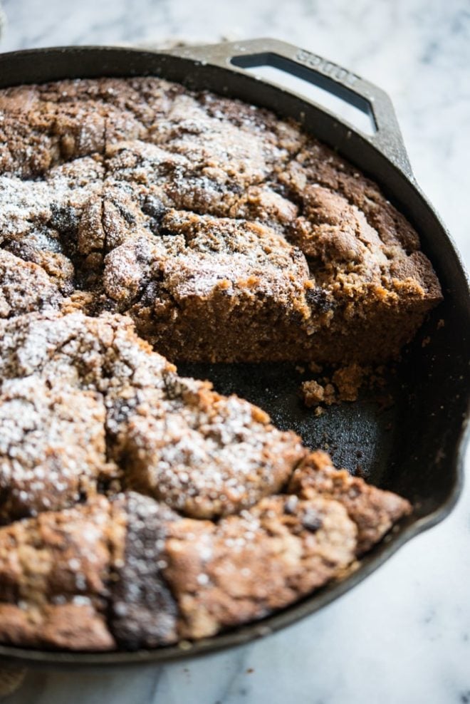 a skillet of chocolate chai swirl coffee cake with one piece missing