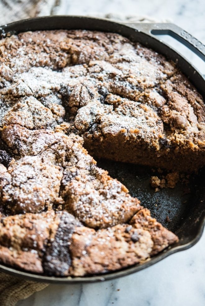 a skillet of chocolate chai swirl coffee cake with one piece missing