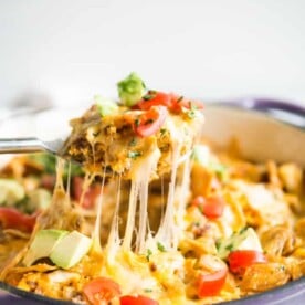 a large spoon pulling a piece of chorizo migas breakfast skillet away from a casserole dish