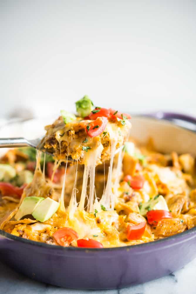 a large spoon pulling a piece of chorizo migas breakfast skillet away from a casserole dish