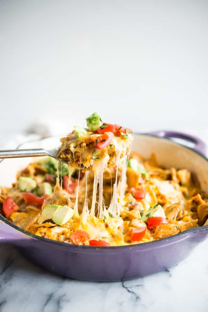 a large spoon pulling a piece of chorizo migas breakfast skillet away from a casserole dish