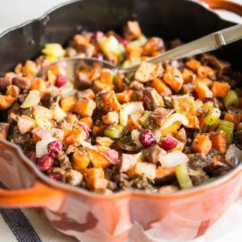 paleo stuffing with sweet potatoes, sausage, and cranberries in a pumpkin-shaped cast iron pot on a marble surface