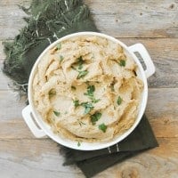 overhead view of a white casserole dish filled with browned butter parsnip mash on top of a green napkin on a wooden table