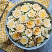 overhead shot of bowl of Cauliflower "Potato" Salad with zig zag yellow napkin on a marble tabletop