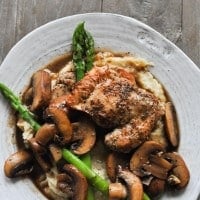 Paleo chicken madeira in a shallow white bowl on a gray wood surface.