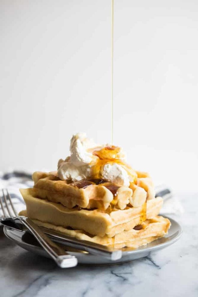 gluten free overnight waffles with whipped cream and a syrup drizzle