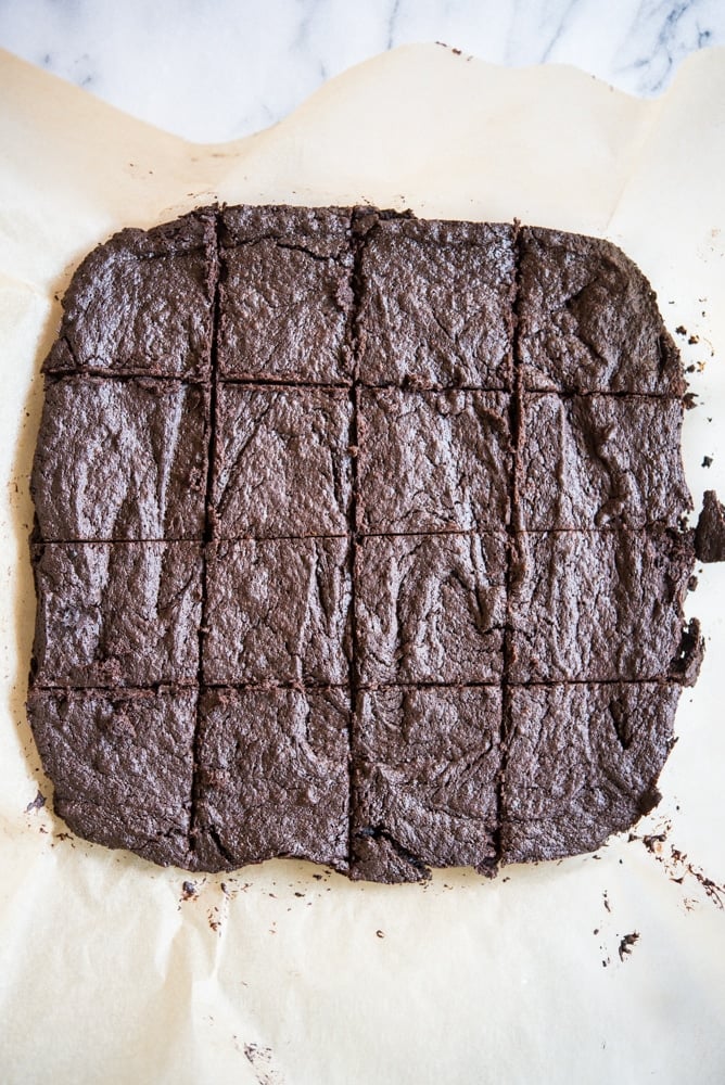 flourless dark chocolate brownies cut into squares sitting on a piece of parchment paper