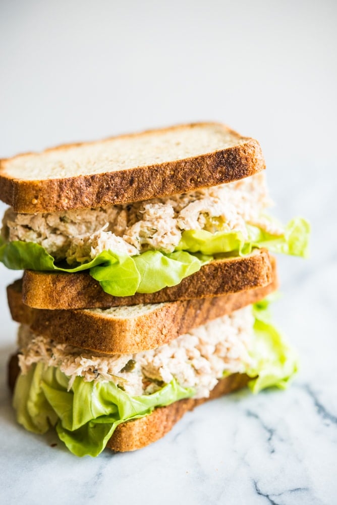 classic tuna salad sandwiches stacked on top of each other on top of a marble board