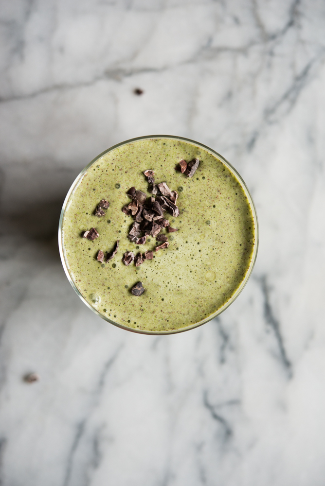 mint chocolate chip green smoothie in a glass on a marble board