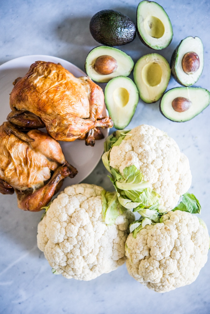 roasted chicken, avocados, and cauliflower on a marble board