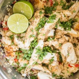 instant pot chicken fajitas and rice in a metal pot garnished with limes and chopped cilantro
