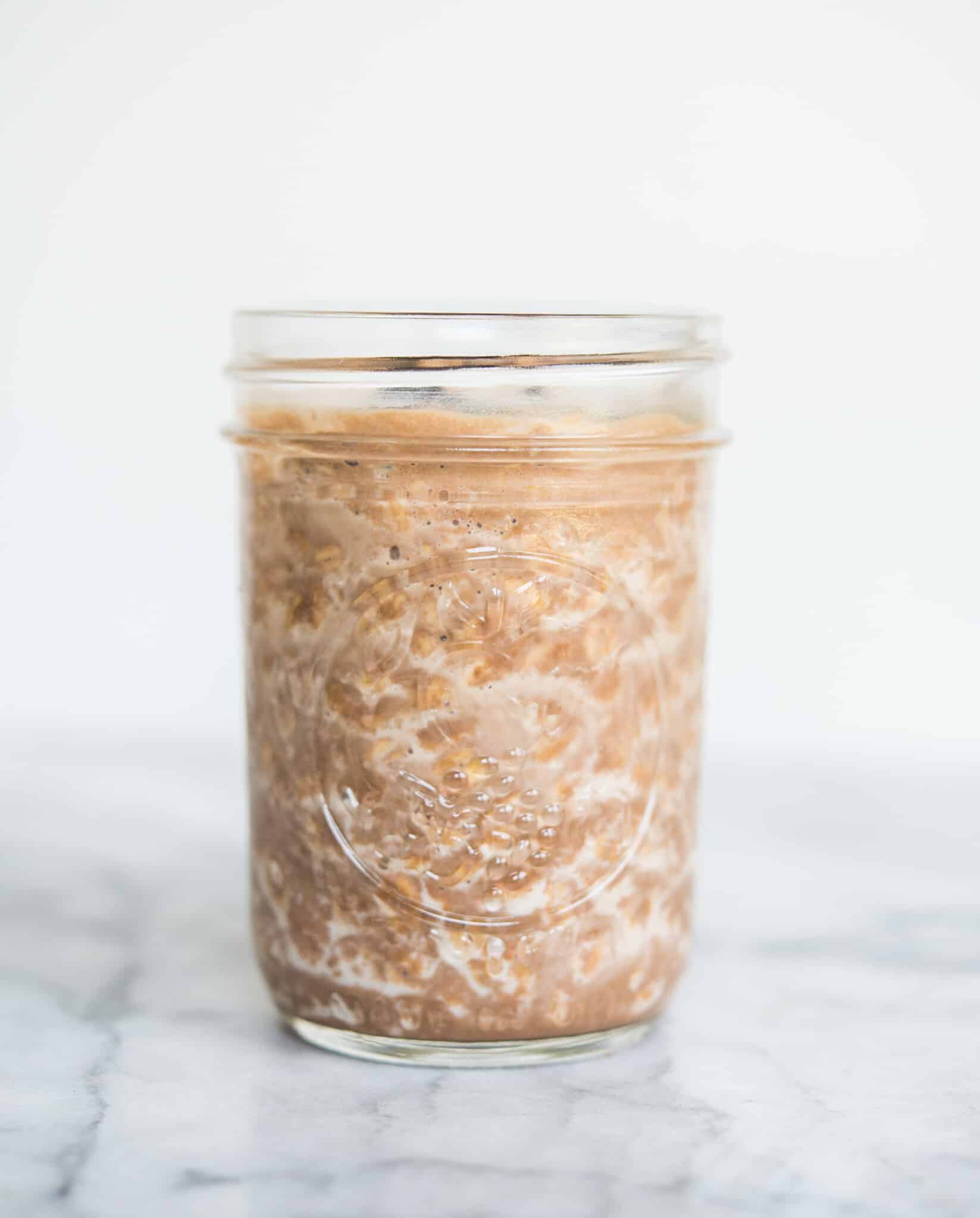 chocolate peanut butter overnight oats in a mason jar sitting on a marble counter