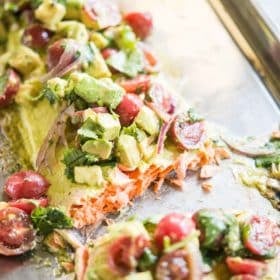 cilantro lime baked salmon topped with tomato avocado salsa on a sheet pan