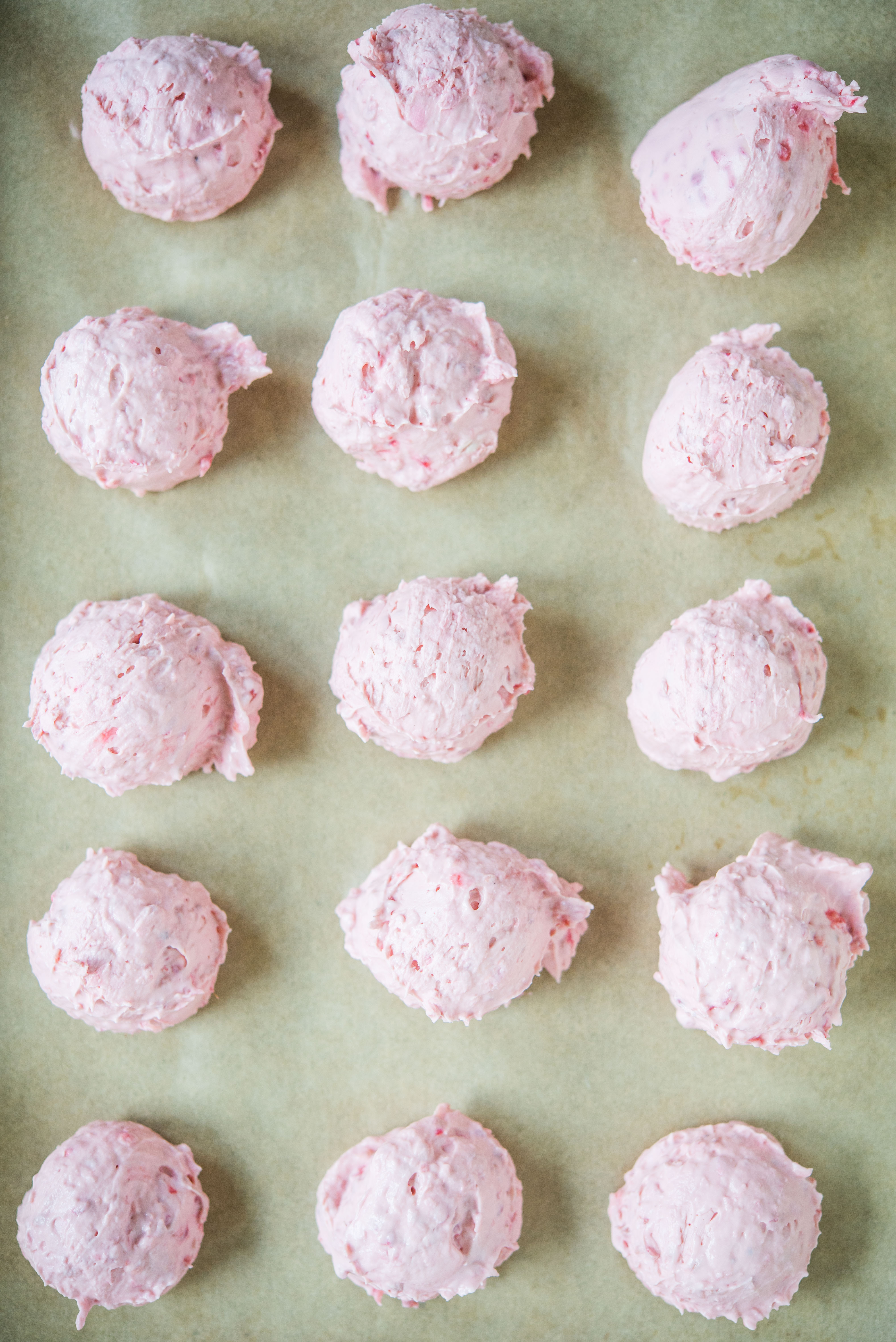 white chocolate raspberry cheesecake fat bombs on brown parchment paper