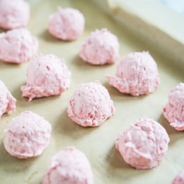white chocolate raspberry fat bombs on a parchment paper lined baking sheet