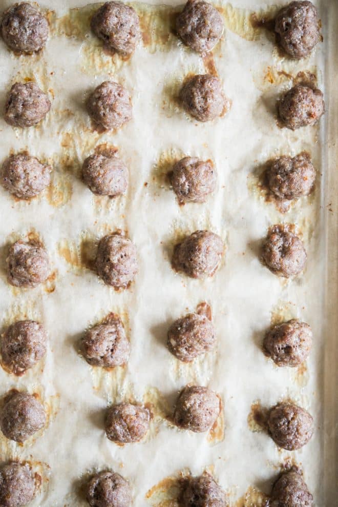 baked breakfast sausage meatballs on a parchment paper lined sheet pan