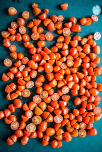 chopped cherry tomatoes on a black cutting board