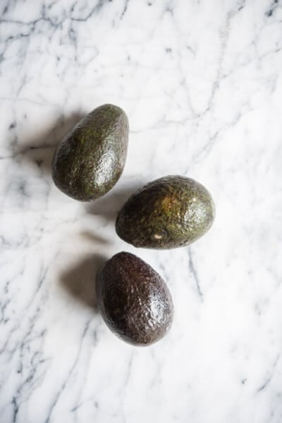 three avocados on a marble board