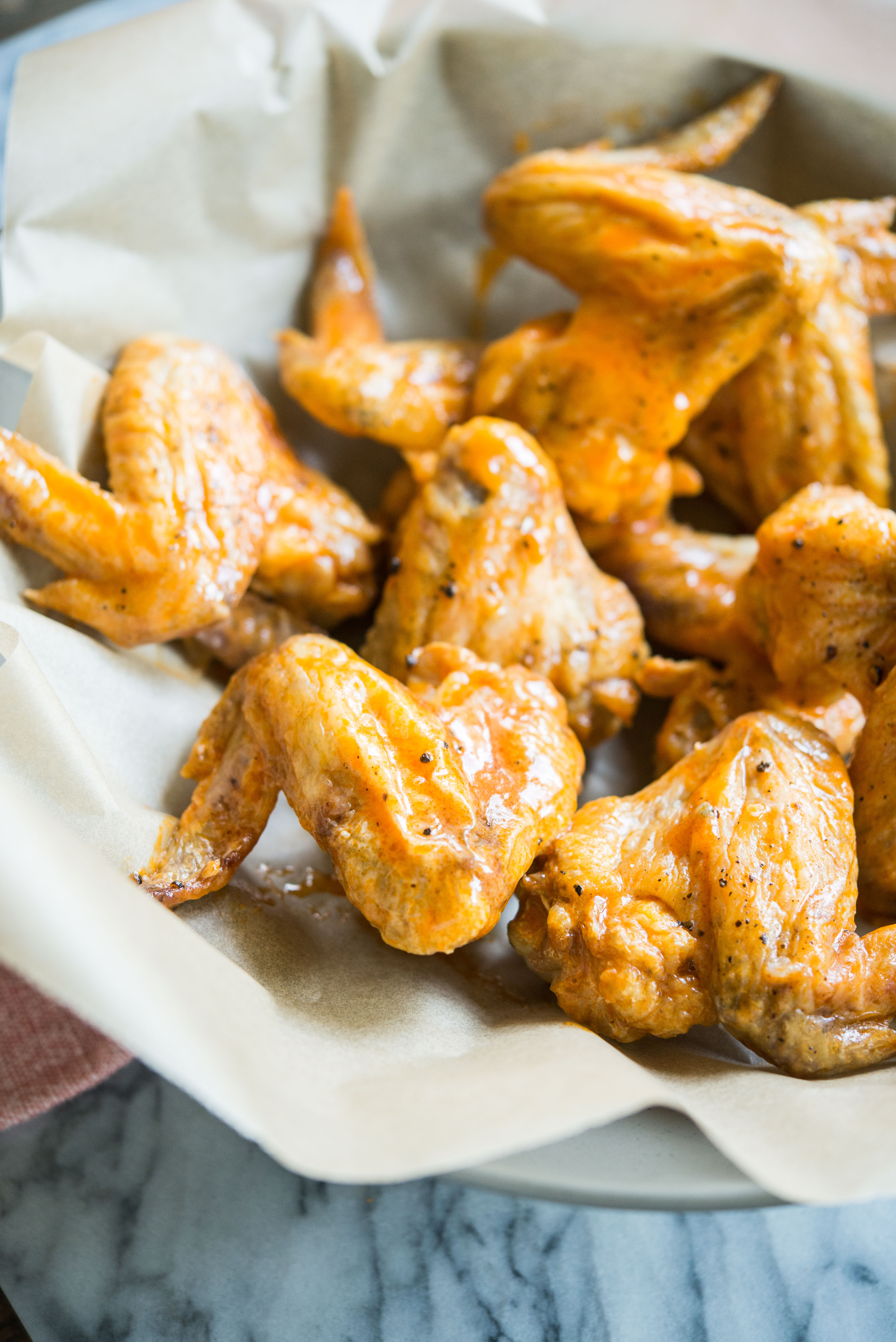 crispy baked buffalo chicken wings in a bowl lined with parchment paper