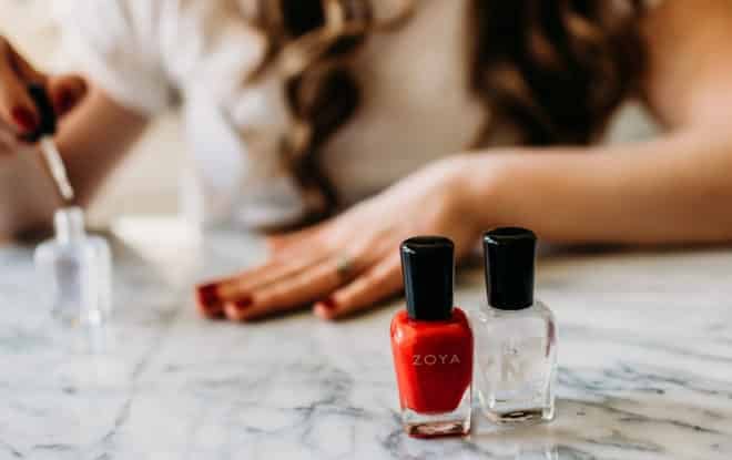 zoya non-toxic nail polish on a marble board in front of a woman painting her nails