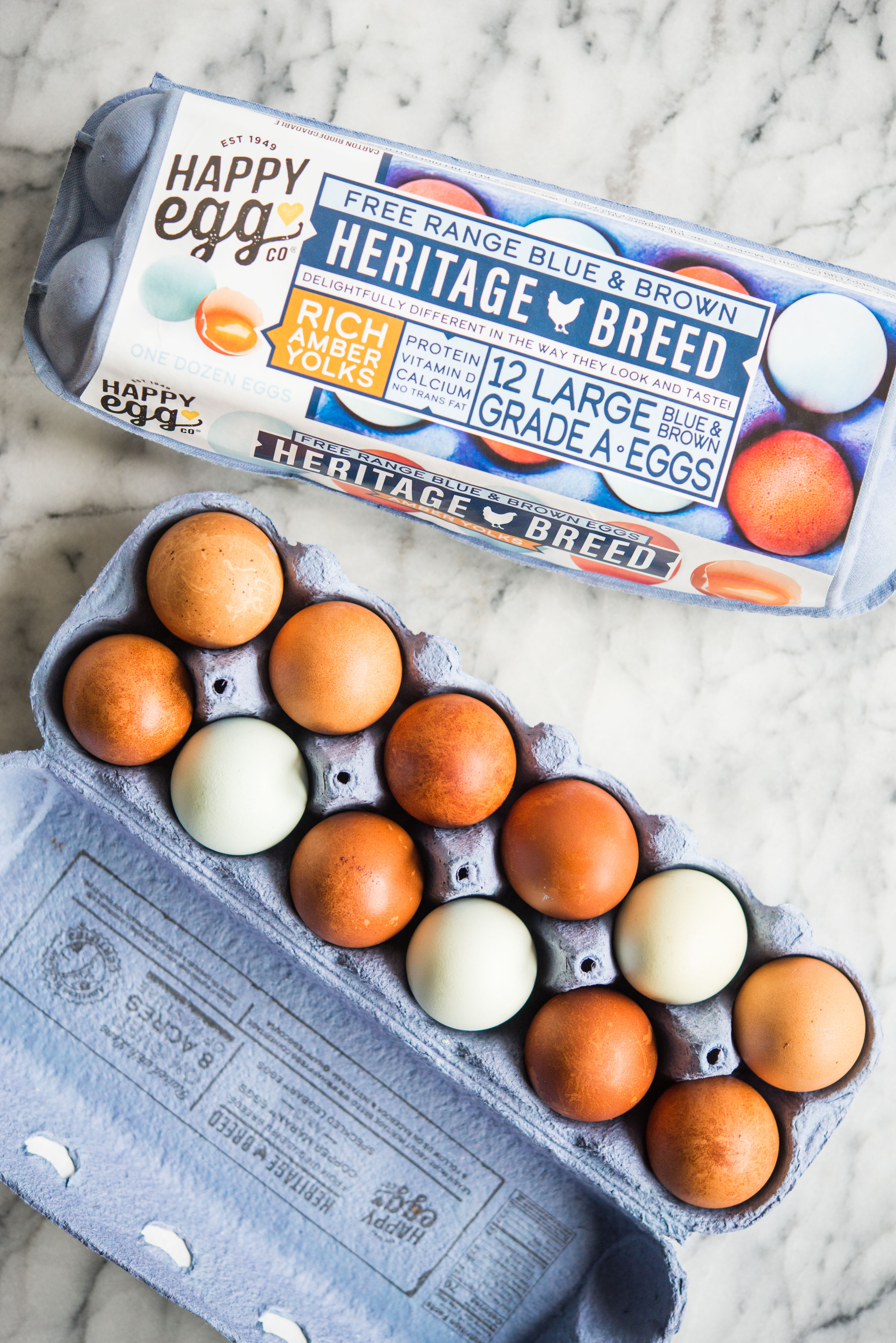 blue and brown eggs in an egg carton on a marble board