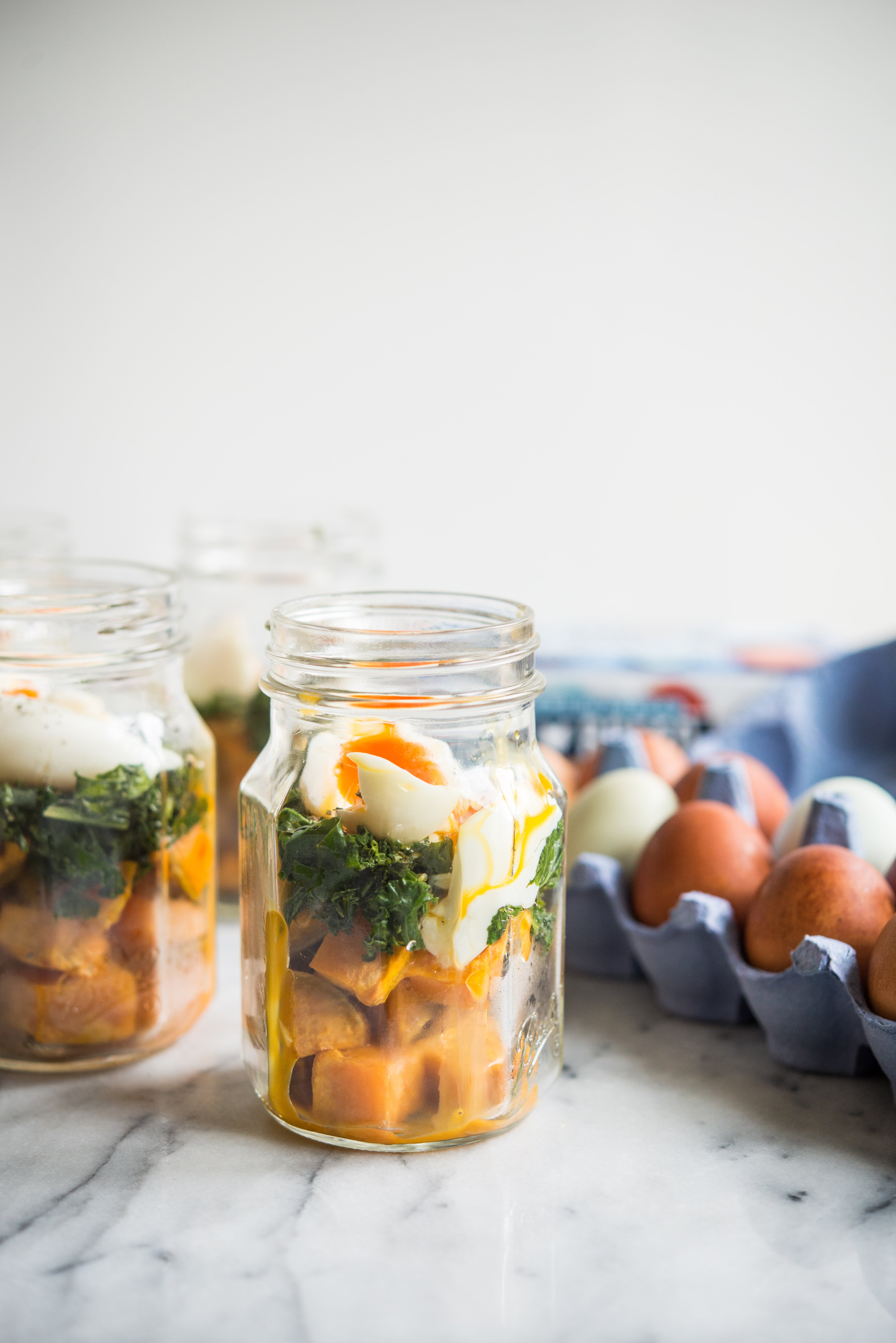 make-ahead balanced breakfast jars - sweet potatoes, kale, and soft boiled eggs in a mason jar on a marble board