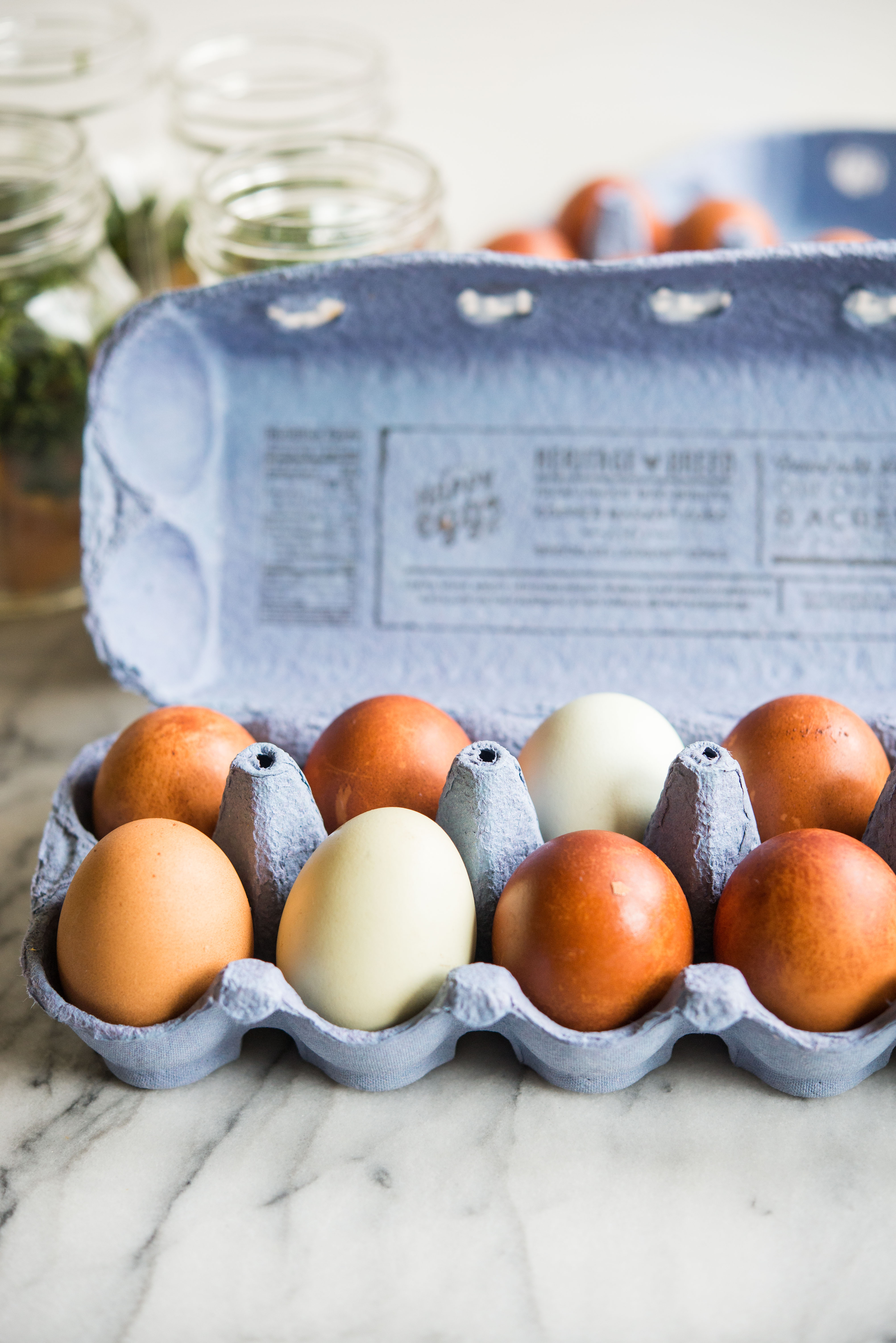 blue and brown eggs in an egg carton on a marble board
