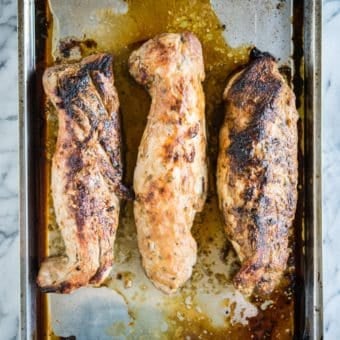 3 baked pork tenderloins on a stainless steel sheet pan