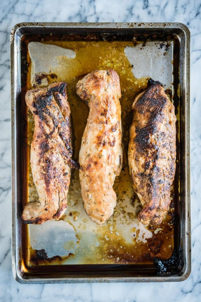 3 baked pork tenderloins on a stainless steel sheet pan