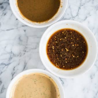 3 pork tenderloin marinades - sesame ginger, maple dijon, and balsamic rosemary in white bowls on a marble countertop