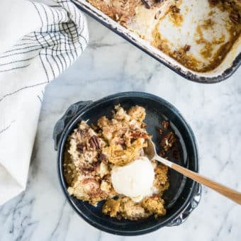 pumpkin pie dump cake in a dark blue bowl with a scoop of ice cream on top