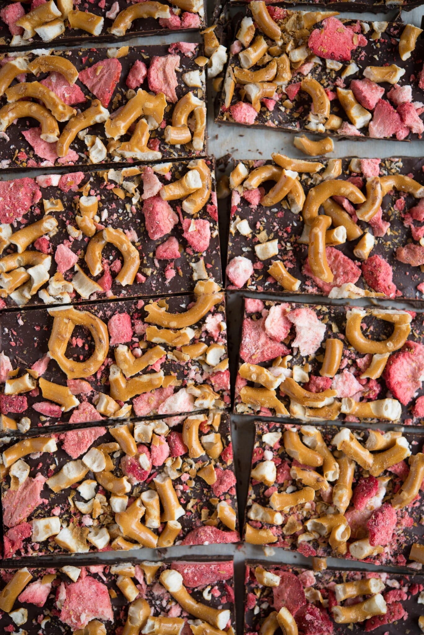 dark chocolate bark with crushed strawberries and pretzels on parchment paper