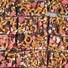 dark chocolate bark with crushed strawberries and pretzels on parchment paper