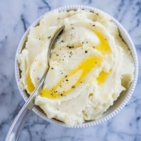 mashed potatoes made in an instant pot in a grey bowl with pools of butter on top sitting on a marble surface