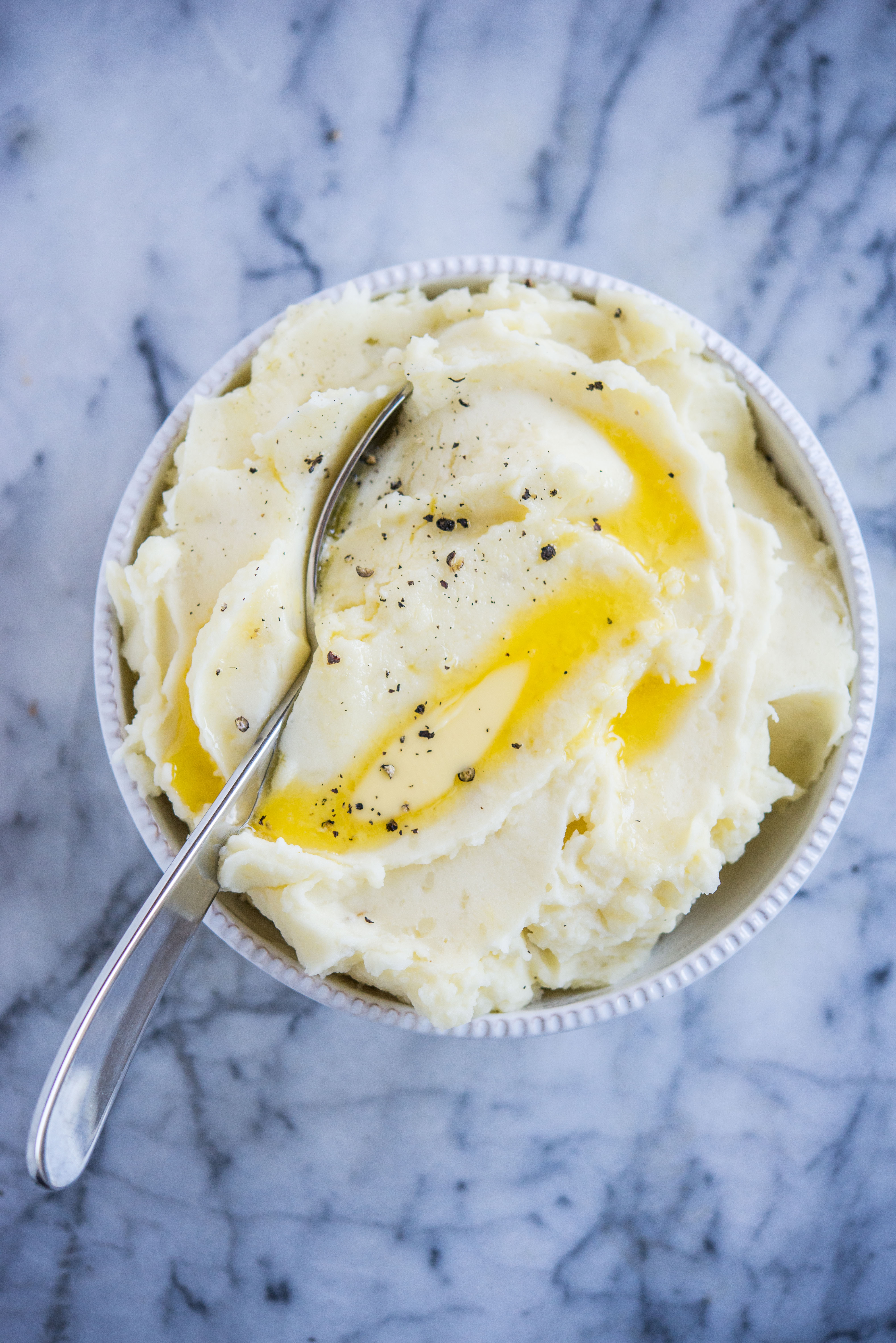 mashed potatoes made in an instant pot in a grey bowl with pools of butter on top sitting on a marble surface