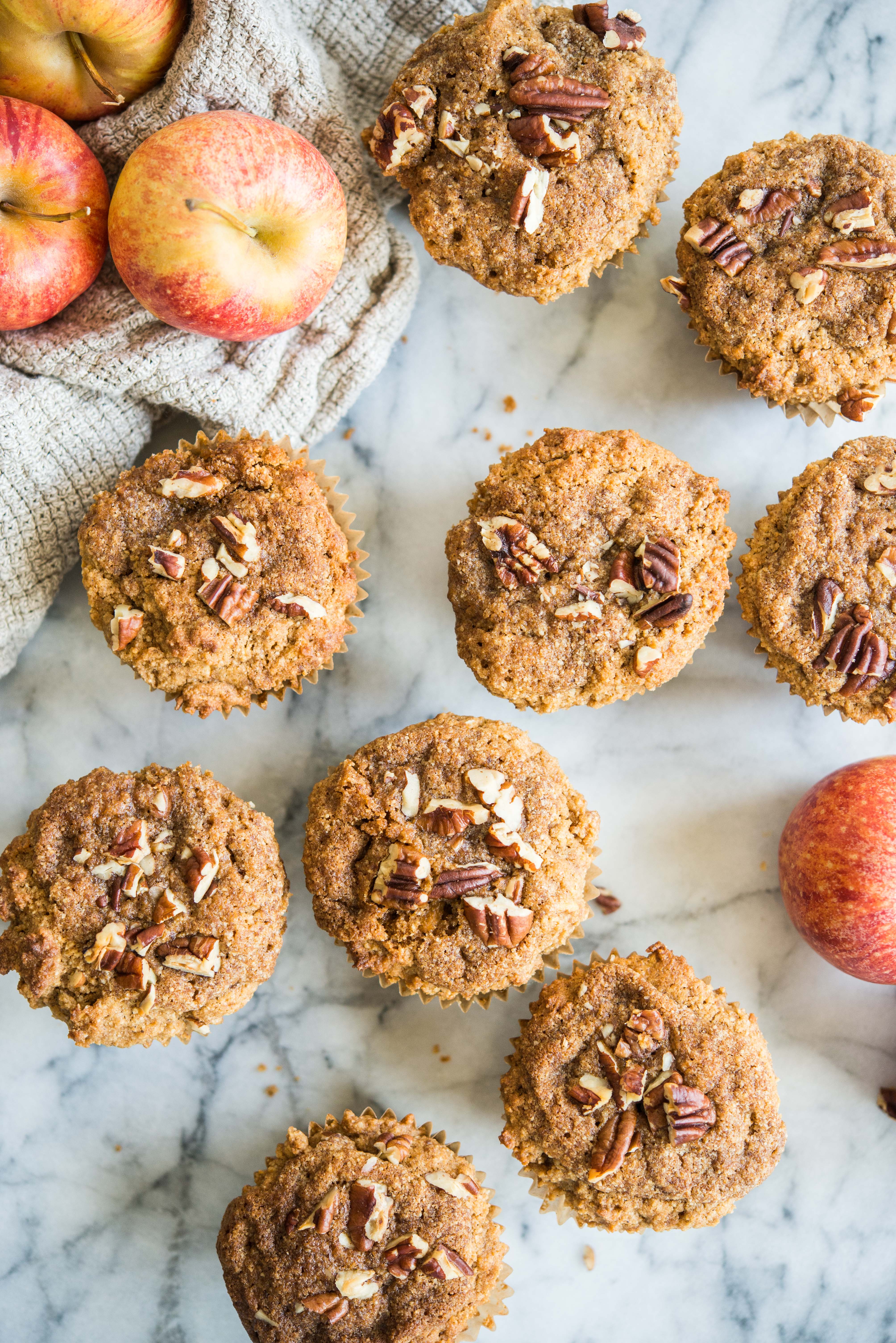 paleo apple cinnamon muffins on a marble board surrounded by apples