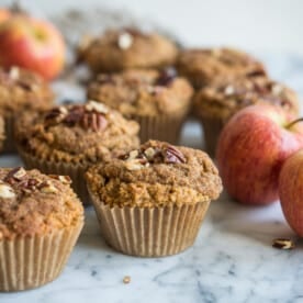 paleo apple cinnaomon muffins on a marble board surrounded by apples