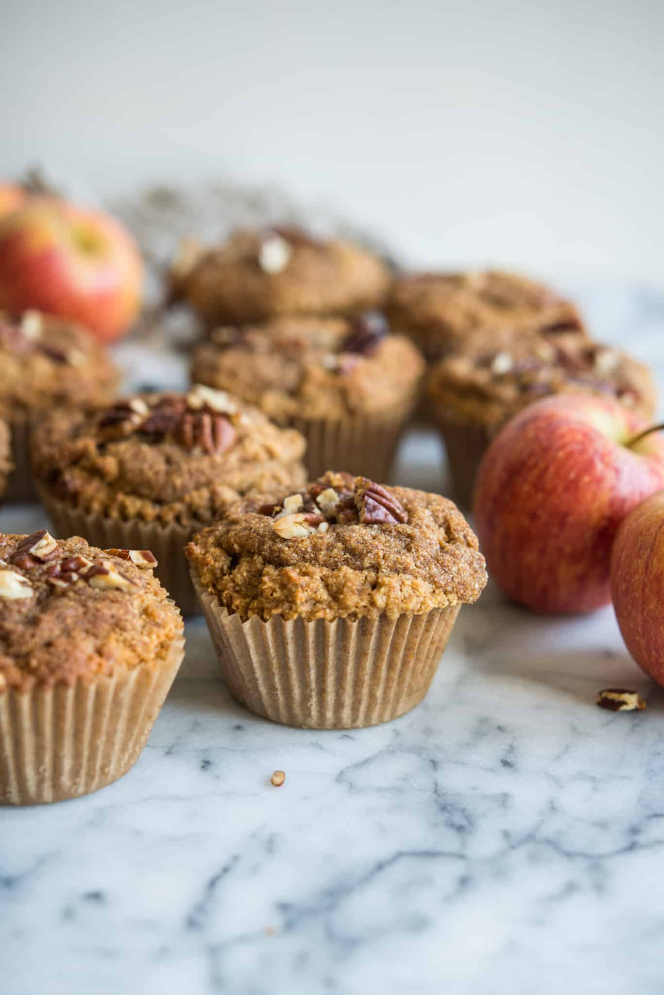 paleo apple cinnaomon muffins on a marble board surrounded by apples