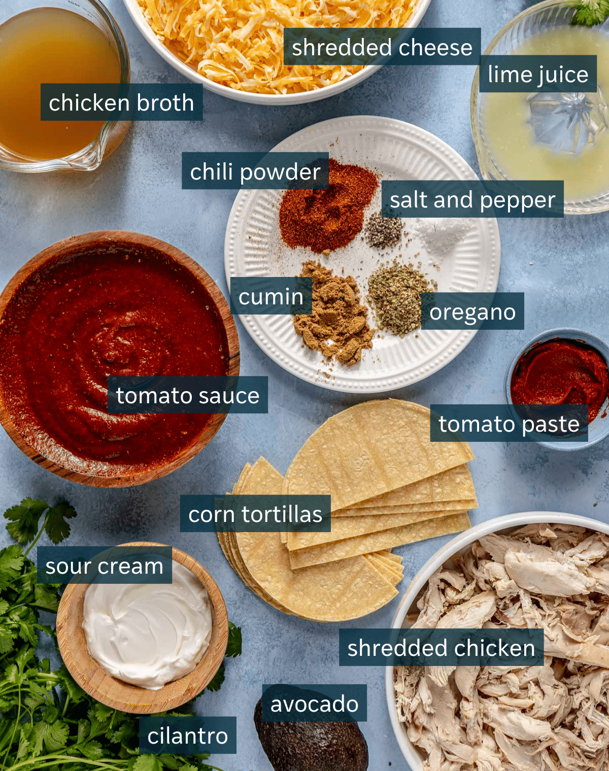 All of the ingredients for chicken enchilada casserole on a blue surface.