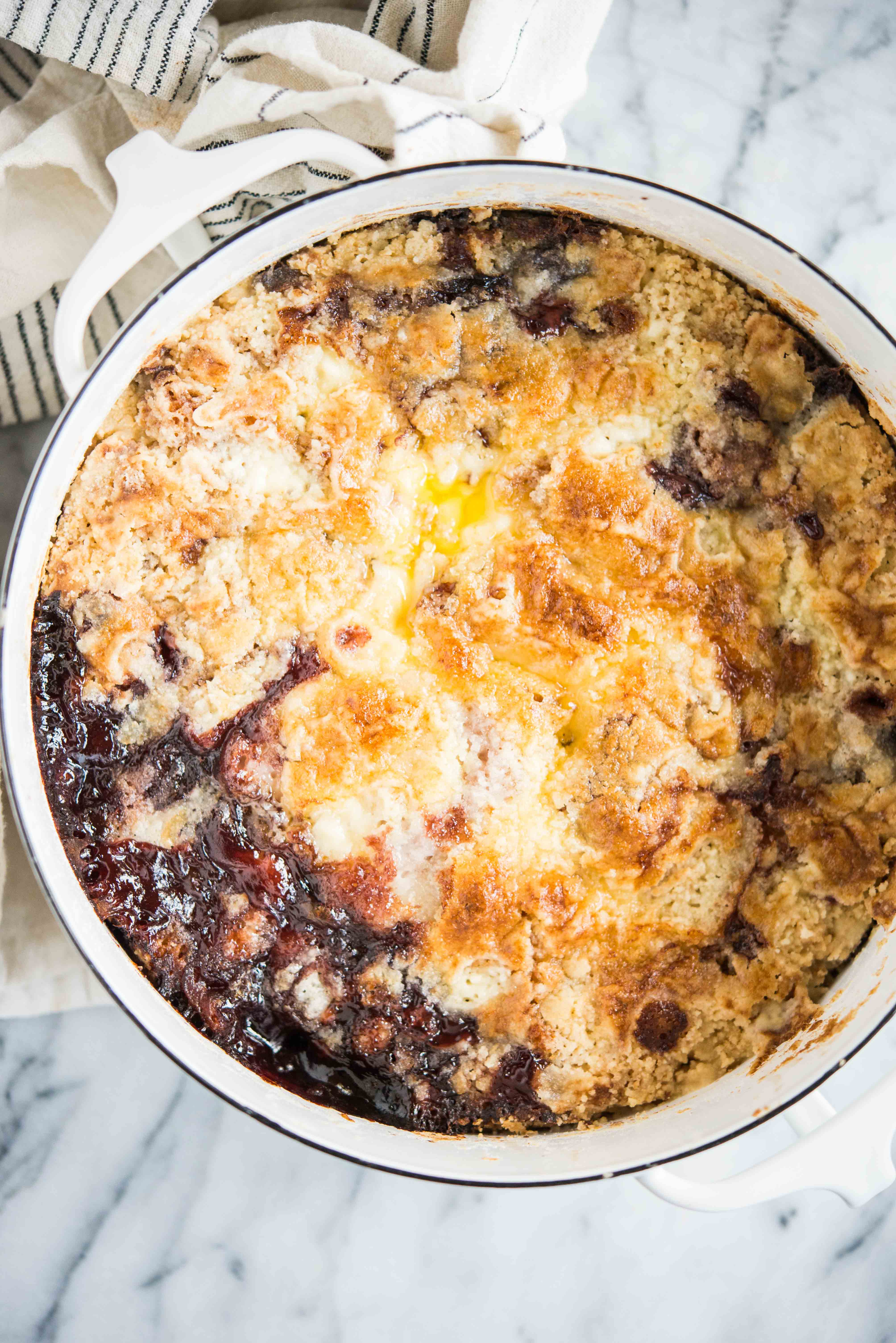 cherry dump cake in a round white dish on a marble surface