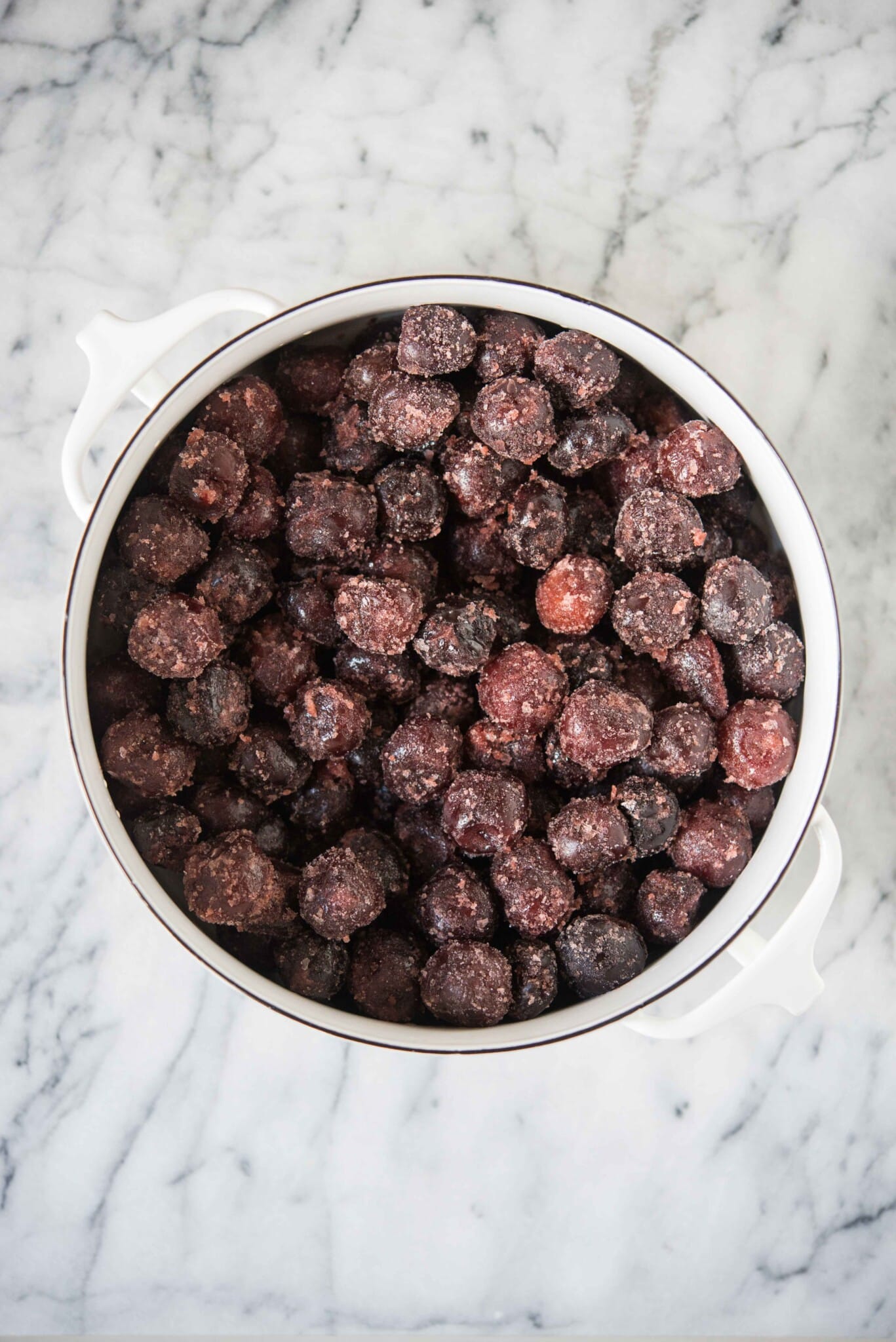 frozen cherries in a round white dish on a marble surface to make cherry dump cake