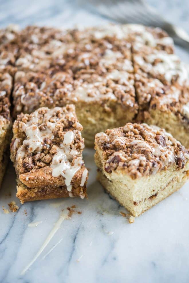 cinnamon roll coffee cake with icing on top cut into squares and placed on a marble surface