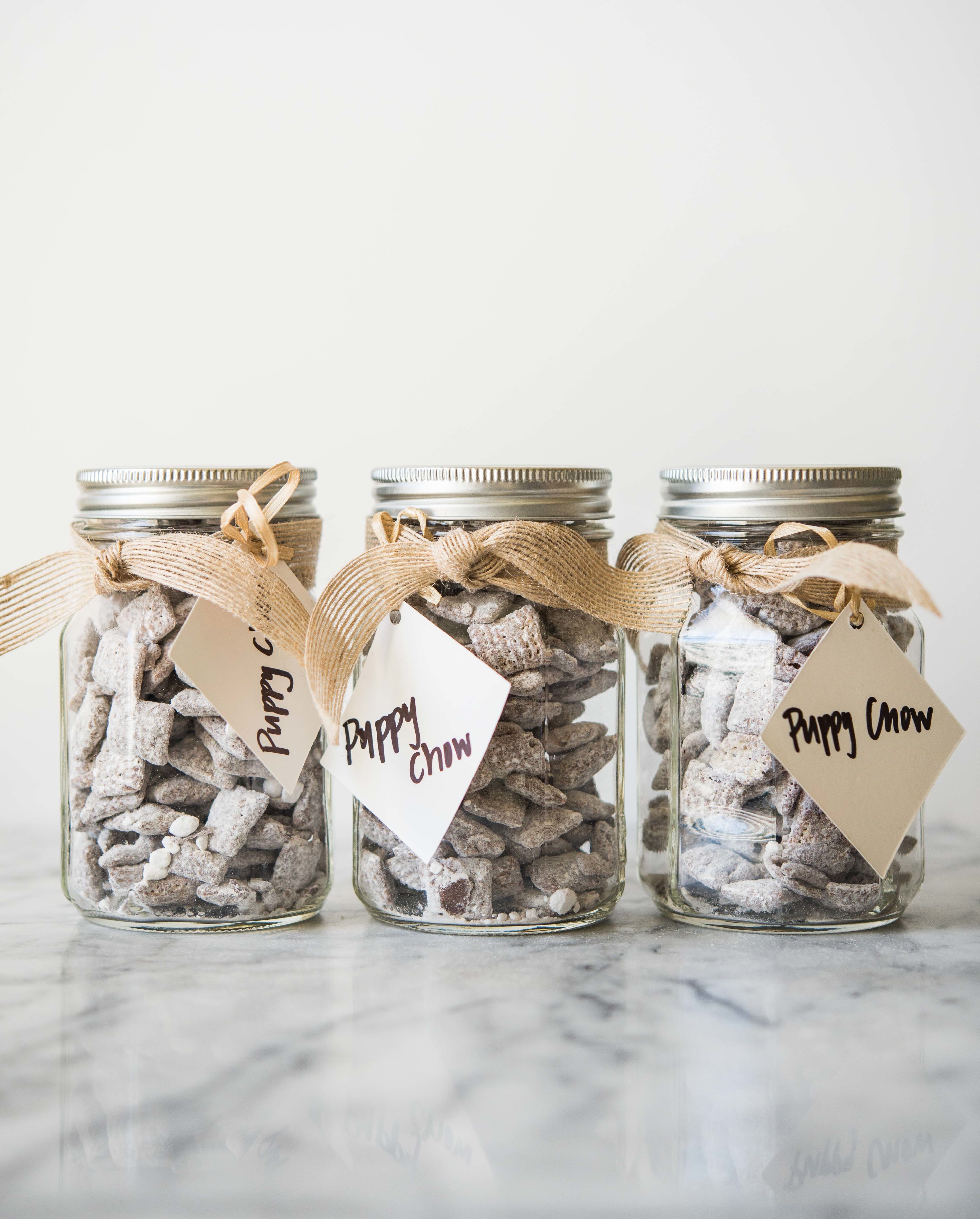 3 jars of puppy chow in glass jars with a brown ribbon wrapped around each and a gift tag attached