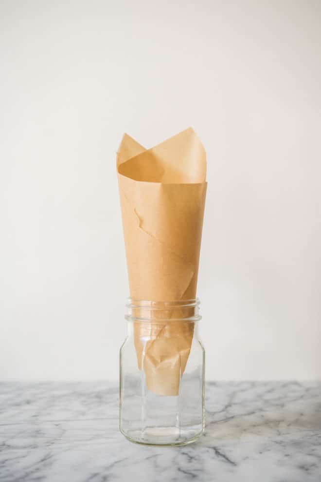 parchment paper cone in a mason jar on a marble surface - how to make puppy chow