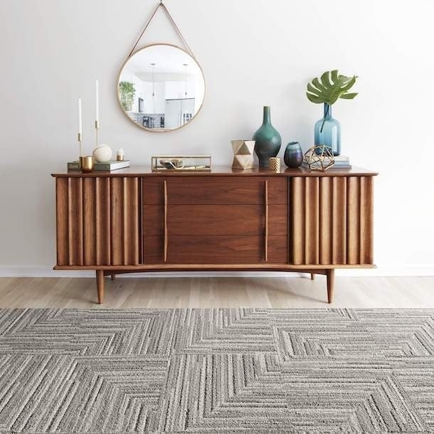 patterned grey and white rug in front of a wooden hutch