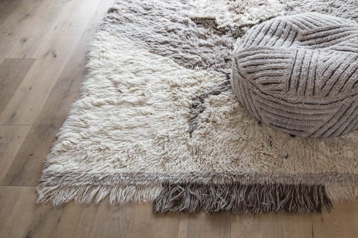 non-toxic rug that is grey and white with a grey cushion sitting on top of it