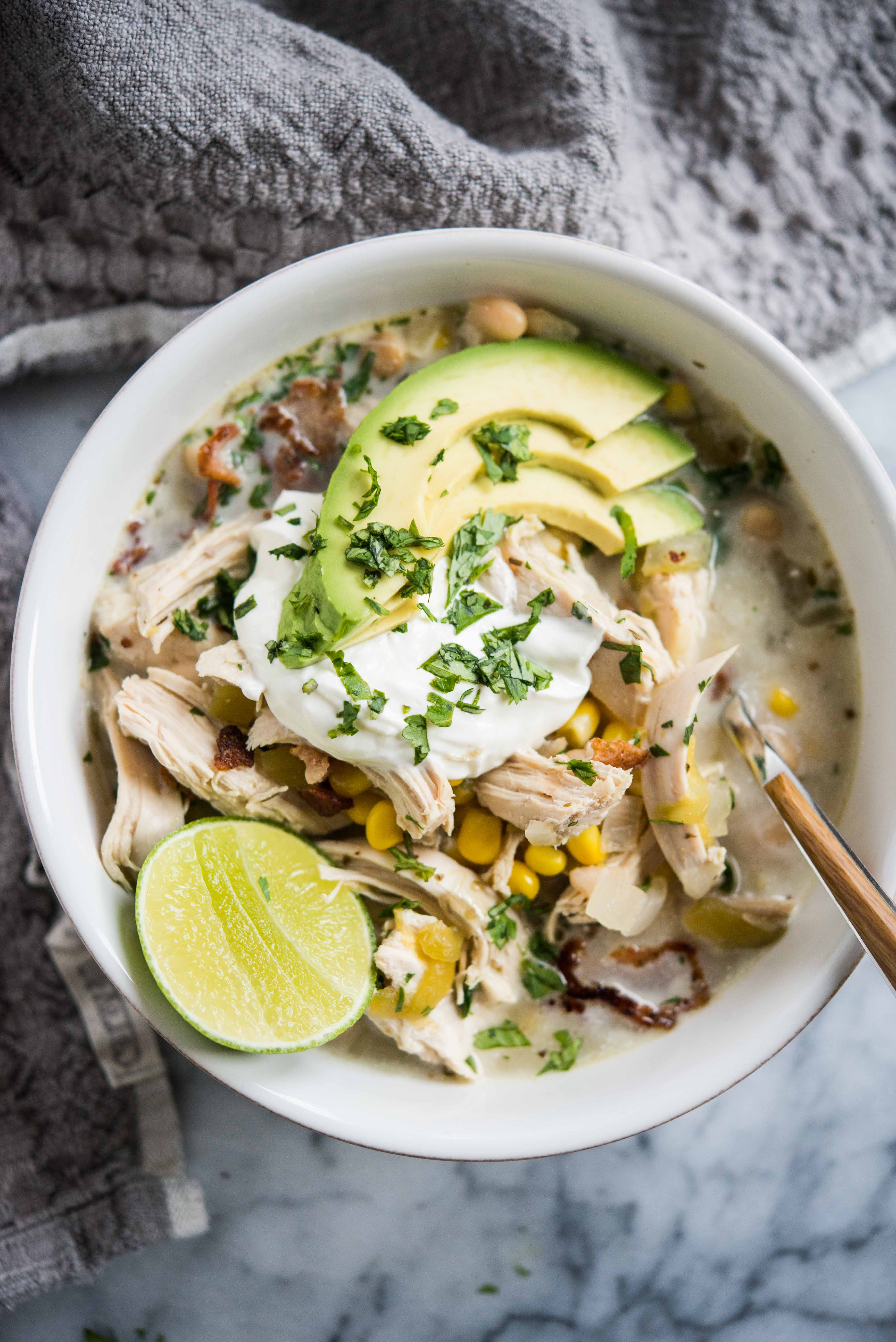 white chicken chili with chopped cilantro on top in a white bowl