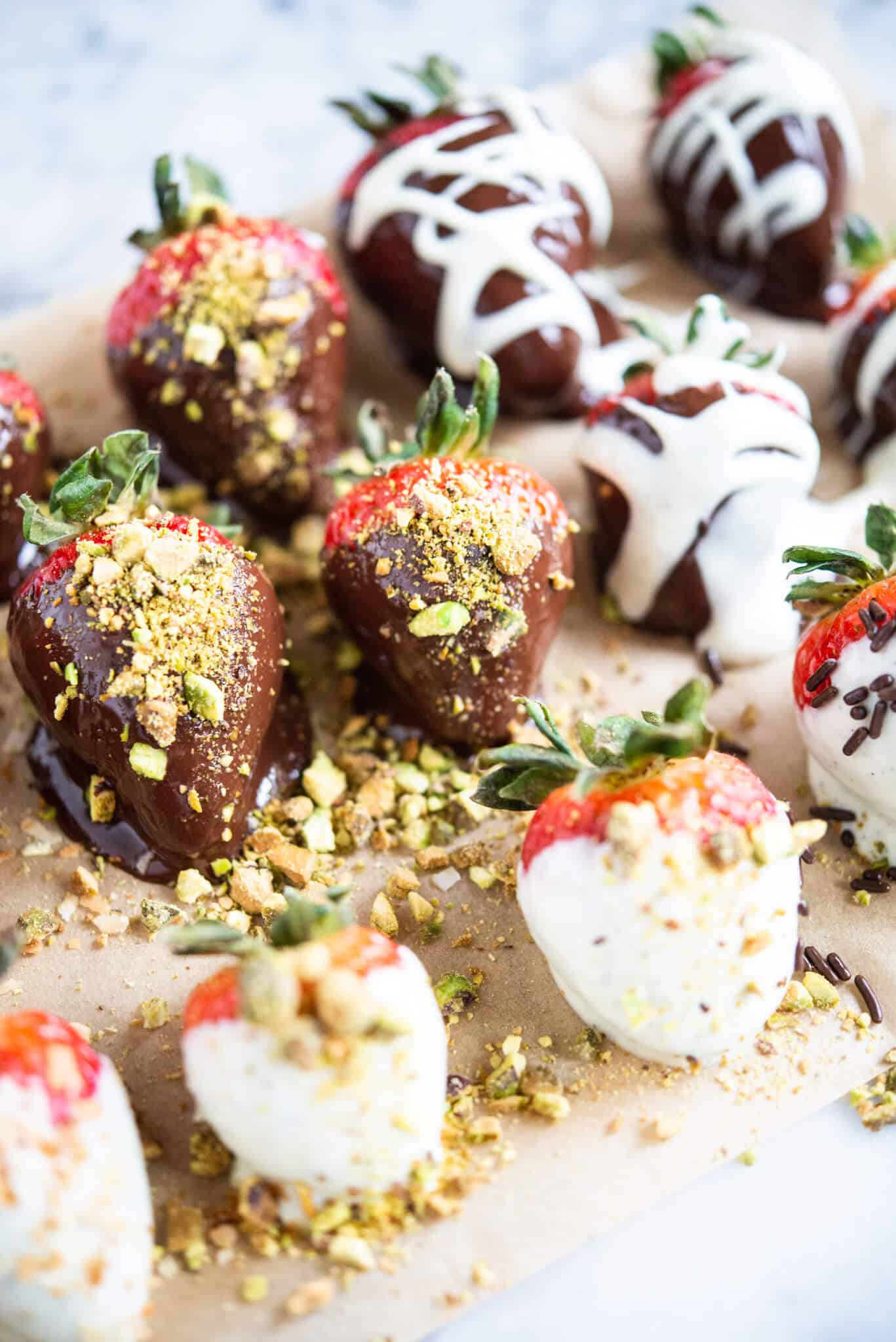 how to make chocolate covered strawberries - chocolate covered strawberries on parchment paper on a marble surface