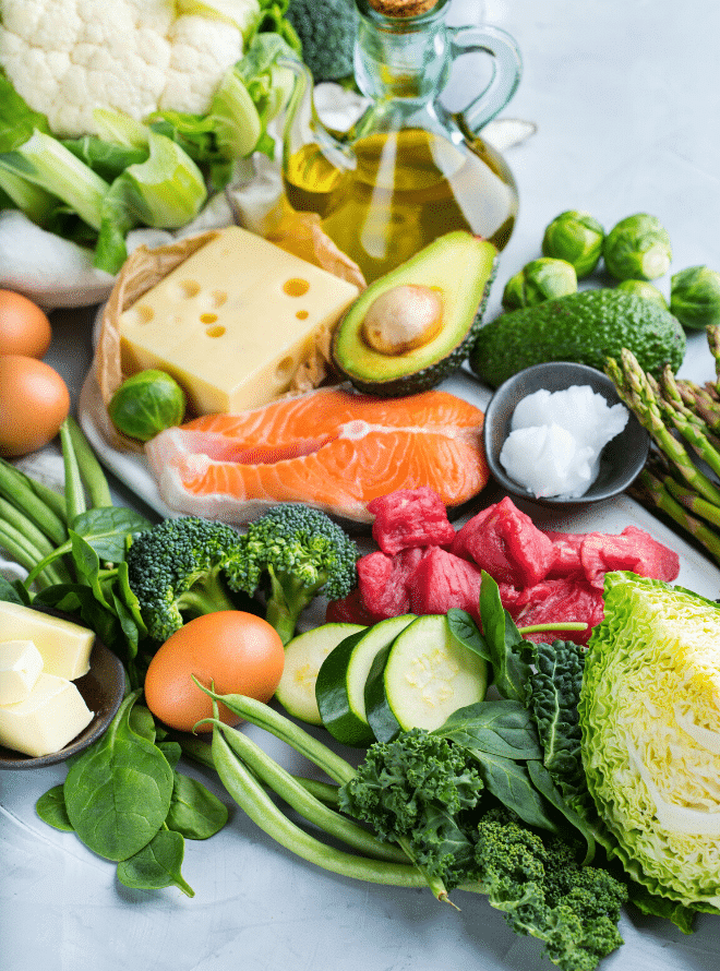 vegetables, olive oil, avocado, and salmon on a grey board - what to eat in your second trimester
